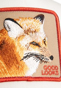 Embroidered patch featuring a fox's face with orange, white, and black details. Text "GOOD LOOKS" in red on a tan background, bordered in red.