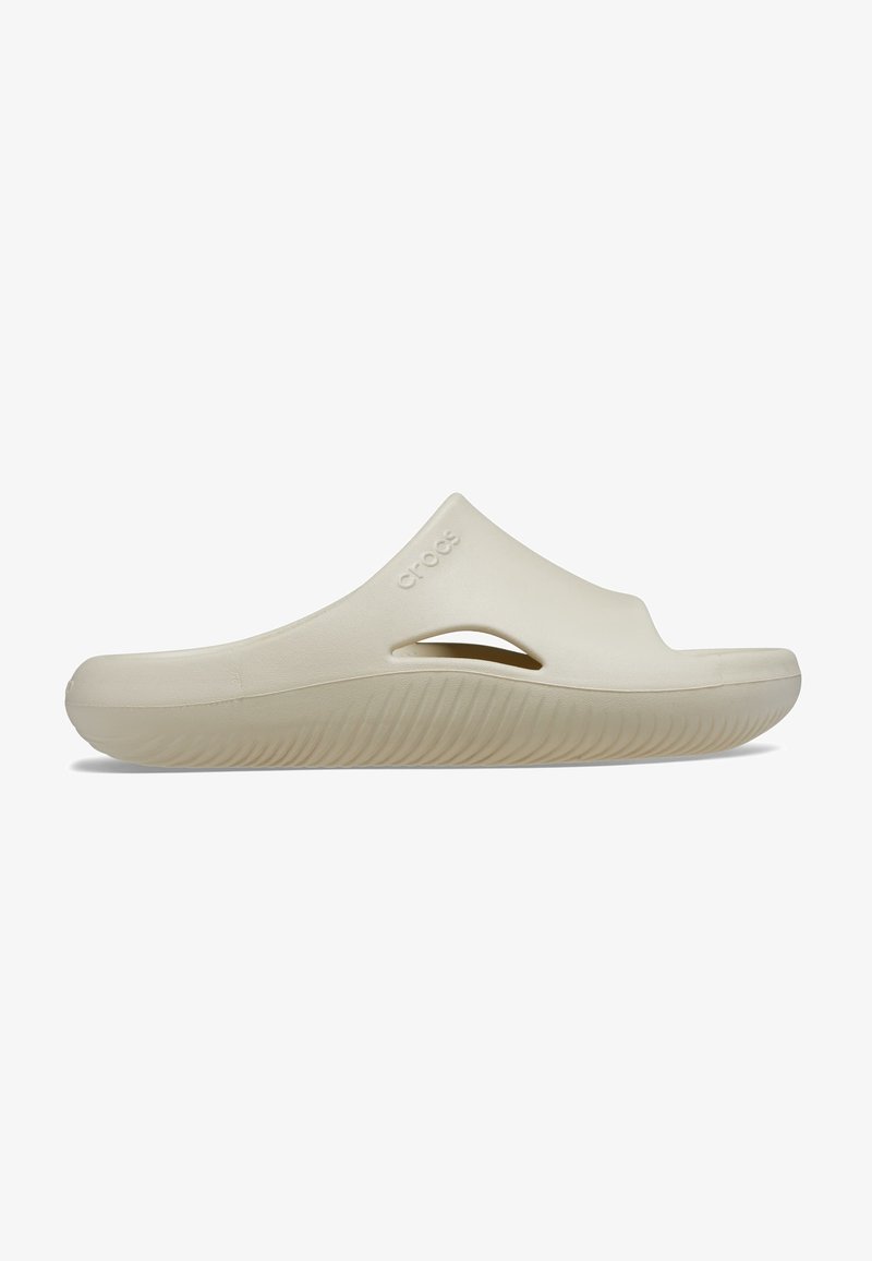 Sandale beige à enfiler avec une finition lisse et mate. Dotée d'une large lanière et d'un design à bout ouvert. Semelle texturée avec des rainures horizontales. Marque "Crocs".