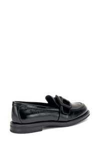 I mocassini in pelle nera presentano una punta arrotondata, un accento a fibbia sulla tomaia e una finitura testurizzata. La suola è piatta e robusta.