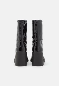 Stivaletti alla caviglia in pelle verniciata nera con una finitura liscia e elegante, tacco a blocco e design arricciato nella parte superiore per una vestibilità aderente.