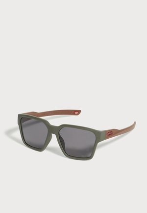 Lunettes de soleil de forme carrée avec des verres foncés, une monture avant vert olive et des branches marron clair avec un petit logo sur le côté.