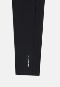 Fekete leggings rugalmas anyagból, testhezálló dizájnnal. "FLASHDRY" felirat fehér színben a szegély közelében, lapos varrásokkal.