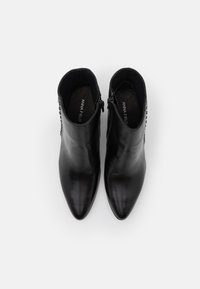 Botas de tobillo de cuero negro con punta afilada, cremallera lateral y tachuelas decorativas a lo largo del tacón. Textura suave y diseño elegante.