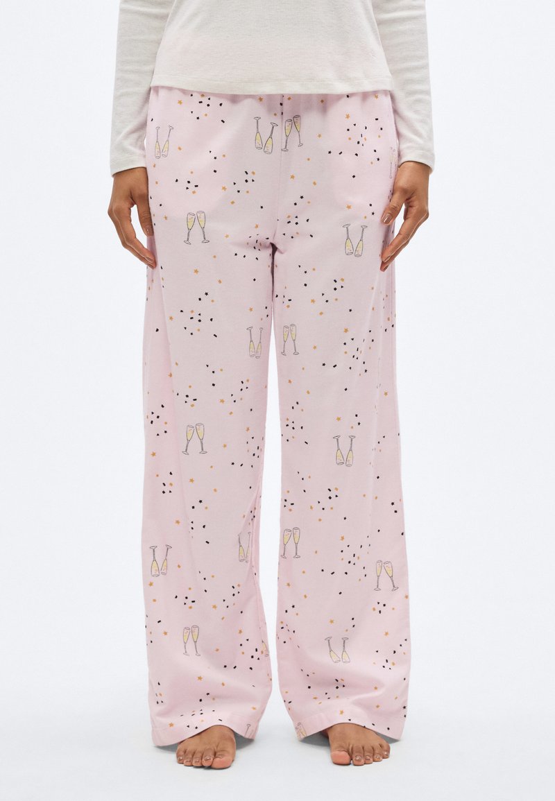 Ροζ παντελόνια πιτζάμας με χαλαρή εφαρμογή, σχέδιο με ποτήρια σαμπάνιας και αστέρια, με μαύρες και πορτοκαλί λεπτομέρειες. Απαλό ύφασμα με ομαλή υφή.