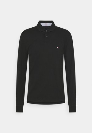 Camisa polo negra de manga larga hecha de algodón, con cuello tipo apuntado, tapeta de tres botones y pequeño logo en el pecho.
