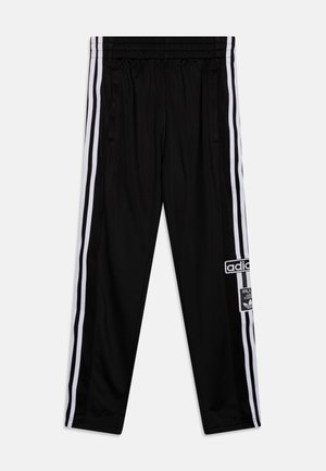 Pantalones deportivos negros Adidas con franjas laterales blancas, cintura elástica, bolsillos con cremallera y parches del logo en la pierna derecha.