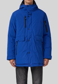 Blaues Puffer-Jacke mit hohem Kragen, Reißverschluss-Brusttasche, Druckknöpfen und zwei vorderen Klapptaschen. Glatte Textur und sportliches Design.