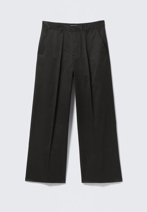 Pantalones negros de pierna ancha con una textura suave, que presentan dos bolsillos frontales y una cintura ligeramente elevada.