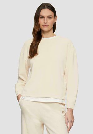 Licht beige sweatshirt gemaakt van zacht materiaal, heeft lange mouwen en een ronde halslijn, met een subtiele hartlogo op de broekzak.