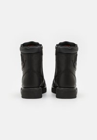 Botas de cuero negras hasta el tobillo con herrajes plateados, cremalleras laterales y diseño en relieve de mano. Suela negra resistente, acabado mate y collar acolchado.