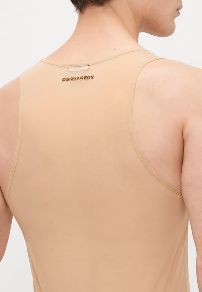 Bēša bezpiedurkņu krekls, izgatavots no gludas, elastīgas auduma. Ar sacensību aizmugures dizainu un nelielu zīmolu etiķeti netālu no kakla izgriezuma.