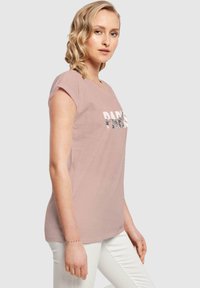 Helles rosa T-Shirt mit kurzen Ärmeln und "PARIS" Grafik in Schwarz und Weiß. Weiches Baumwollmaterial, lässiger Schnitt, runder Ausschnitt.