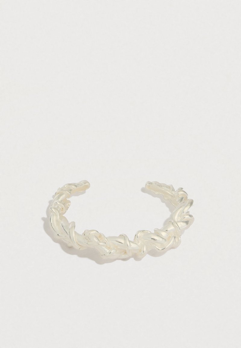 Pulseira tipo bracelete feita de metal em tom prateado torcido, com design trançado, extremidades abertas e textura suave.