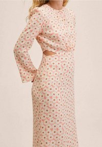 Vestido de manga larga en crema claro con un estampado floral de flores rosas y marrones, que presenta un detalle de corte en el costado y una silueta ajustada.