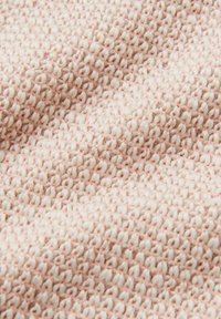 Tessuto testurizzato in rosa chiaro, caratterizzato da un motivo intrecciato con fili alternati più spessi e più sottili, che crea una superficie morbida e tattile.