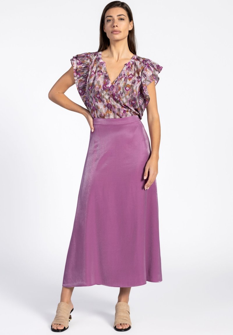 Paarse maxi-rok met een satijnen afwerking, gecombineerd met een gebloemde blouse met vlindermouwen en een diepe V-halslijn.