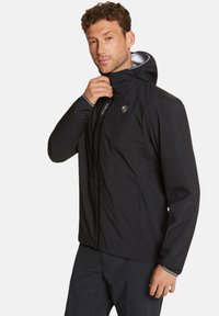 Chaqueta negra resistente al agua con capucha, cierre frontal con cremallera y detalle de logo. Cuenta con puños elásticos y una textura suave para mayor comodidad.