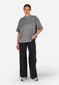 Hall area oversized hallituspusa lühikeste varrukatega, millel on soonikkoes ümar kaelus ja diskreetne logo. Kombineeritud laia jalgadega mustade teksade ja tossudega.