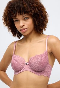 Rózsaszín csipkebrá, virágmintával, alátámasztó huzalokkal, selymes pántokkal és egy kis masni díszítéssel a középen. Texturált és puha felület. 