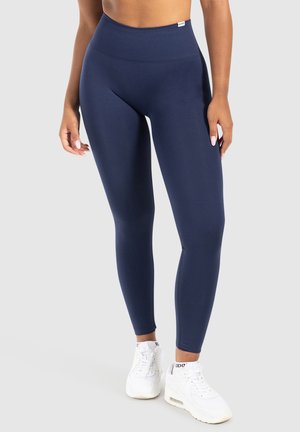 Leggings a vita alta blu navy realizzati in tessuto elastico, con una superficie liscia e una discreta etichetta logo sulla vita.