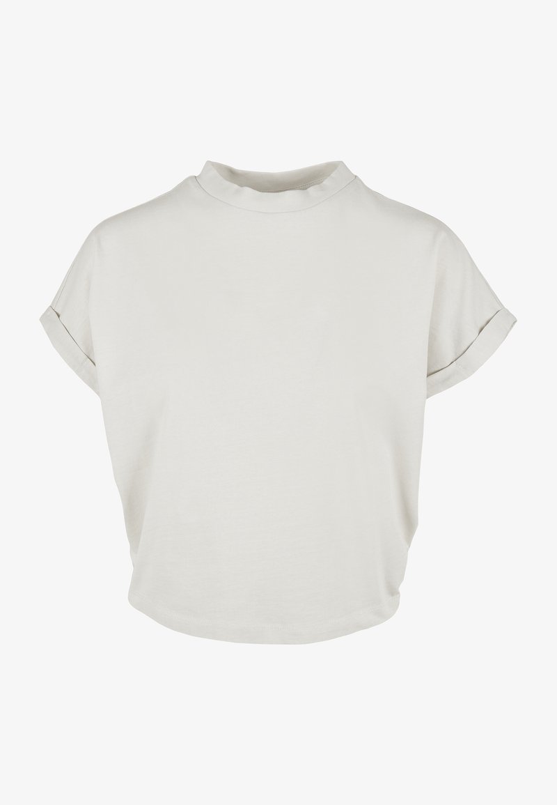 Chemise beige clair à manches courtes avec col montant, texture douce en coton, coupe décontractée et détails de revers roulés. Design lisse et minimaliste.