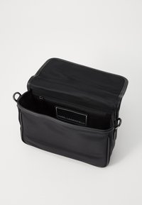 Saco de tecido preto com fecho em zip. Apresenta uma textura suave, design retangular e fecho de press�ão. O interior inclui um bolso com fecho.