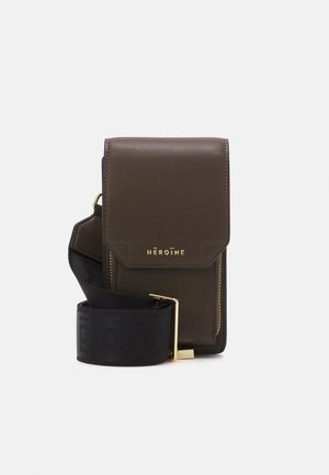 Bruine leren crossbodytas met klepsluiting, gouden hardware en een zwarte riem met geperst logo. Rechthoekige vorm met een gladde textuur.