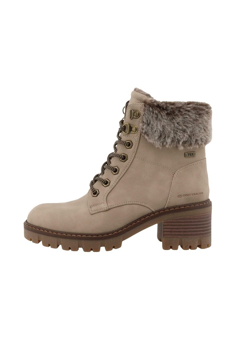 Bottines en suède beige avec une bordure en fausse fourrure, bout rond, œillets en métal et un talon bloc avec une semelle striée pour l'adhérence.