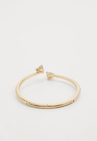 Bracciale a manica in tono oro con superficie liscia, caratterizzato da due accenti di pietre trasparenti triangolari alle estremità e un sottile meccanismo a cerniera.