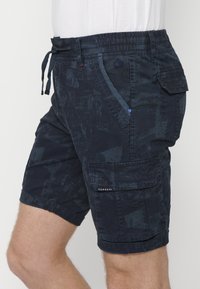 Mörk marinblå cargo-shorts i texturerat tyg. Har elastisk midja med snörning, sidofickor och en lapplåda på benet.