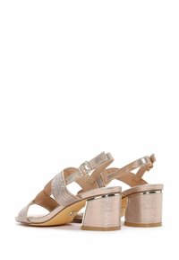 Sandales à talons avec brides en or rose métallique, présentant un dessus texturé avec des accents scintillants et un talon bloc géométrique chunky.