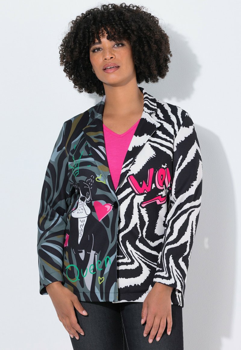Blazer multicolore con motivi a strisce zebrate e astratti, arricchito da un'illustrazione grafica di un cane e del testo; nei colori nero, verde e rosa su un tessuto misto.