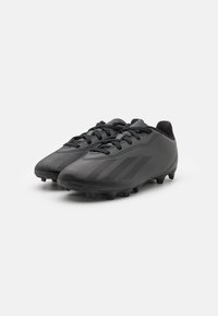 Botas de fútbol negras con un diseño elegante, superficie texturizada, sistema de cordones y franjas más oscuras en contraste. Clavos de goma en la suela para mayor tracción.