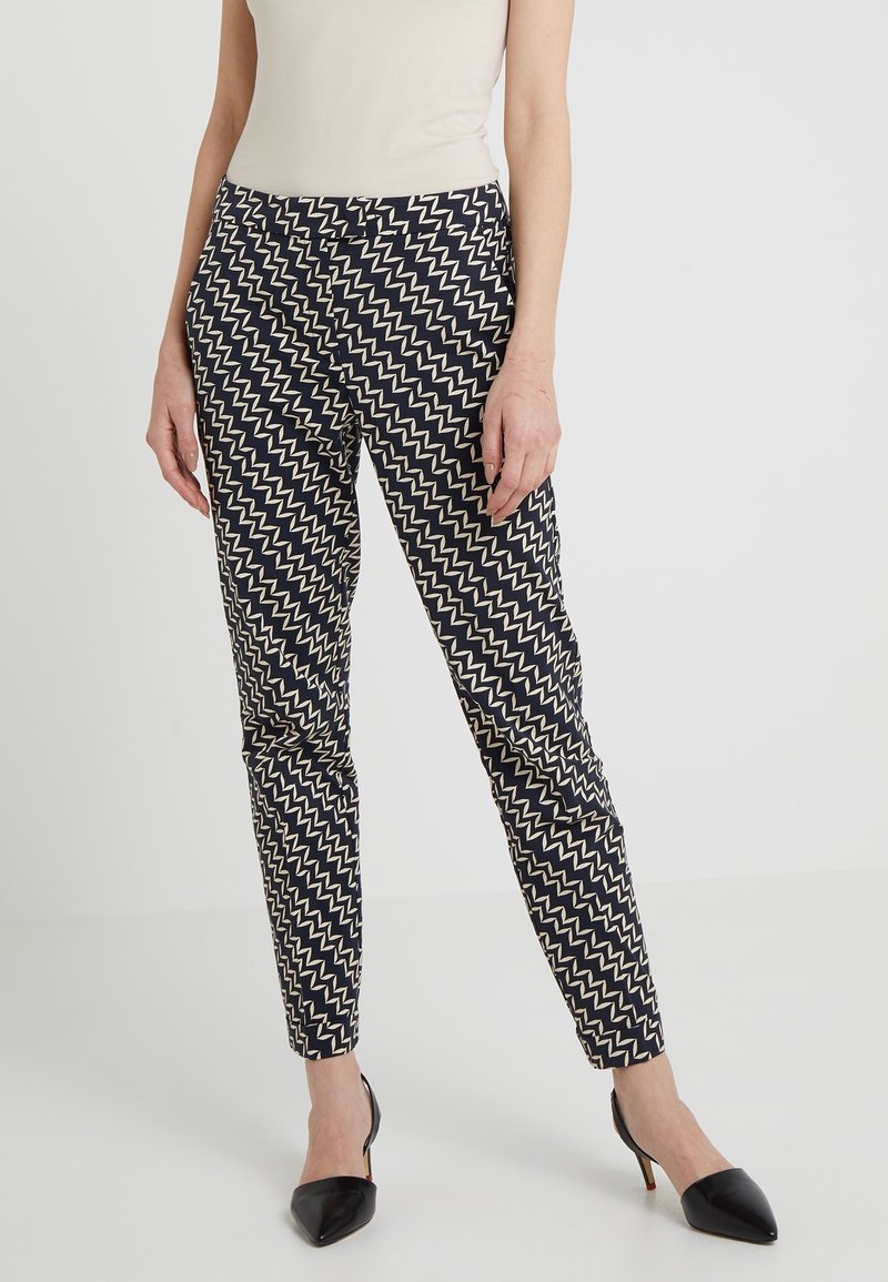 Navy and cream zigzag patterned trousers with a slim fit, made of a smooth fabric, featuring a button closure and belt loops.