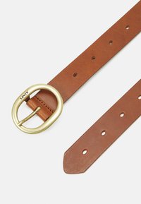 Ceinture en cuir brun avec une grande boucle en laiton circulaire et plusieurs trous d'ajustement sur toute sa longueur. Texture lisse et extrémité effilée.