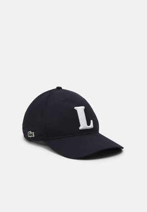 Marineblaues Basecap mit einem weißen, gestickten "L" auf der Vorderseite und einem kleinen grünen Krokodil-Logo an der Seite. Aus Baumwolle, mit gebogenem Schirm.