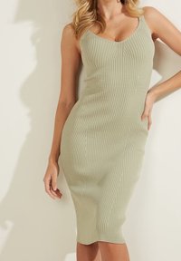 Sukienka dzianinowa w kolorze jasnej zieleni, z dopasowaną sylwetką, okrągłym dekoltem i długością do połowy łydki. Gładka faktura z subtelnymi pionowymi liniami.