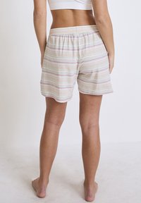 Lätta, randiga shorts i mjukt tyg, med en avslappnad passform och ett elastiskt midjeband. Färgerna inkluderar pastellrosa och blå ränder på beige.