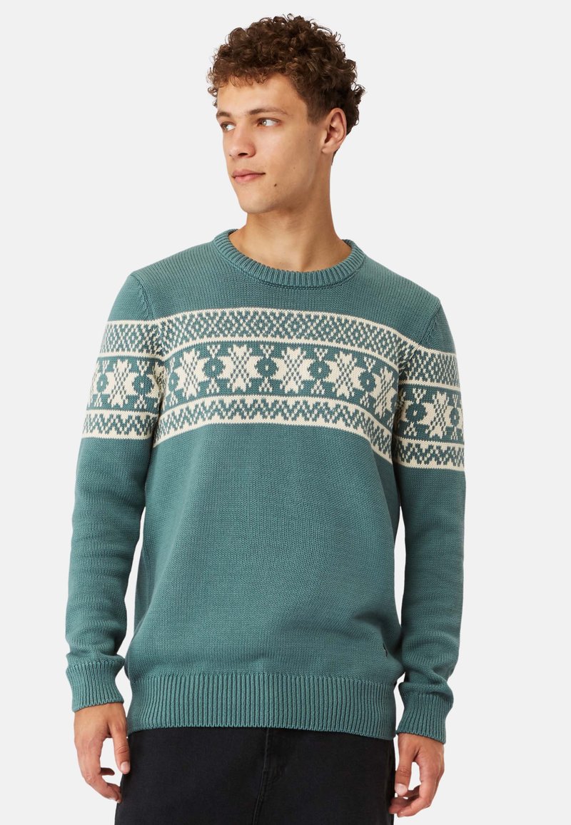 Teal knitted sweater with a white geometric pattern across the chest, round neckline, and ribbed cuffs and hem. Textured fabric.