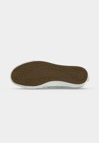 Semelle d’une chaussure avec une bande de roulement en caoutchouc marron texturé et un bord blanc, montrant la marque Dockers Footwear.