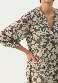 Leichtes, durchscheinendes Kleid in Creme mit schwarzem Blumenmuster, mit V-Ausschnitt, lockerer Passform und gerafften Ballonärmeln.