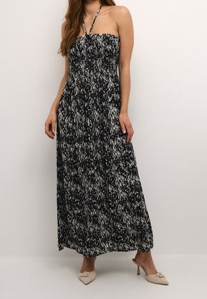 Robe maxi dans un motif abstrait noir et blanc, avec un haut sans bretelles en smock et un tissu fluide qui atteint les chevilles.
