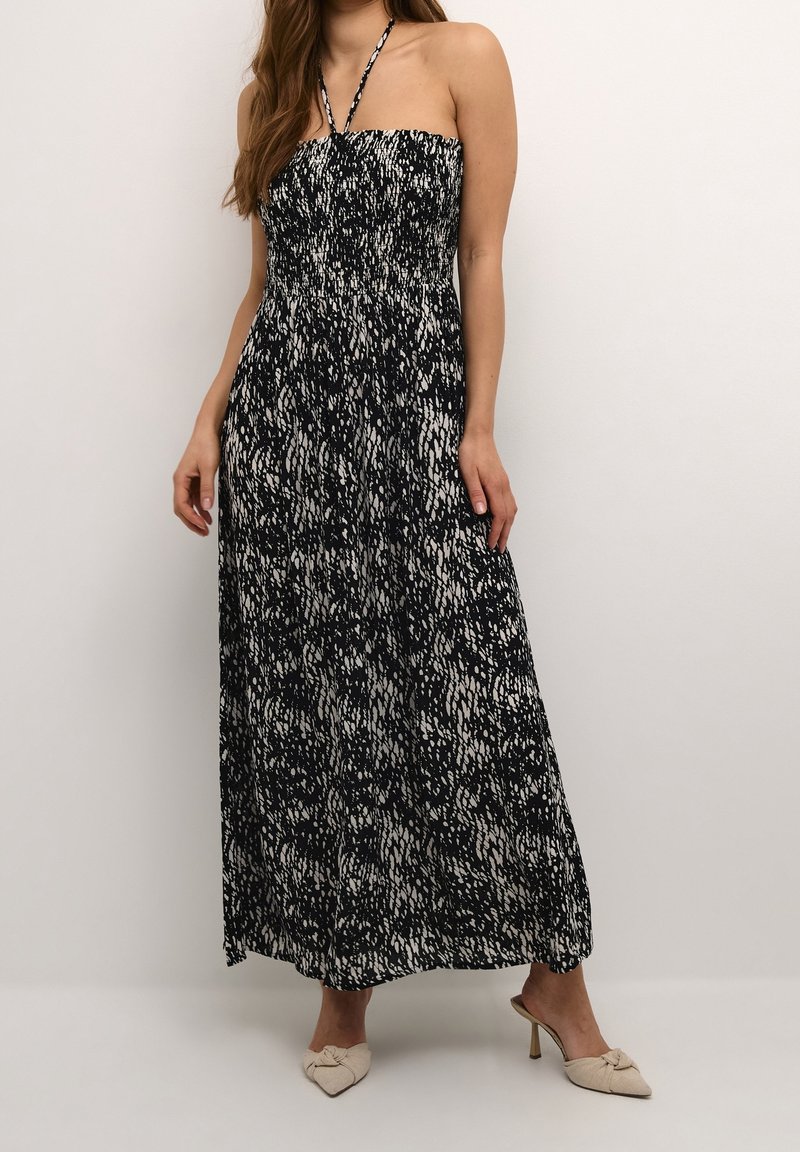 Robe maxi dans un motif abstrait noir et blanc, avec un haut sans bretelles en smock et un tissu fluide qui atteint les chevilles.
