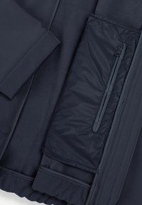 Giacca navy con un morbido interno in fleece, una tasca con zip e un esterno liscio con dettagli di cucitura discreti.