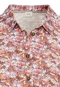 Bloemrijke button-up shirt in paars, oranje en witte patronen. Heeft een puntige kraag en bruine knopen op een lichte stof.