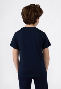 Camiseta de algodón de color marino con mangas cortas y escote redondo, que presenta un diseño sencillo y una textura suave. Se muestra la vista trasera.
