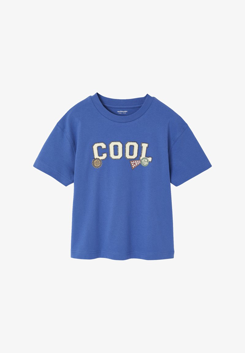 Blue cotton t-shirt featuring the word "COOL" in cream letters, accented with various patches, including a circular logo and a rectangular badge.