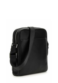 Borsa a tracolla in pelle nera con texture liscia, forma rettangolare, chiusura superiore con zip e tracolla regolabile. Dettaglio tasca laterale visibile.