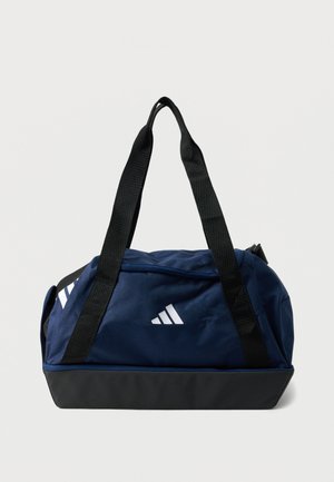 Temno modra in črna Adidas torba za šport z črnimi naramnicami in belim logotipom na enobarvni podlagi.