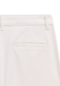 Helle beige Stoffhose, die den Bund, die Gürtelschlaufen und eine einzelne Gesäßtasche zeigt. Die Textur wirkt glatt und sauber.
